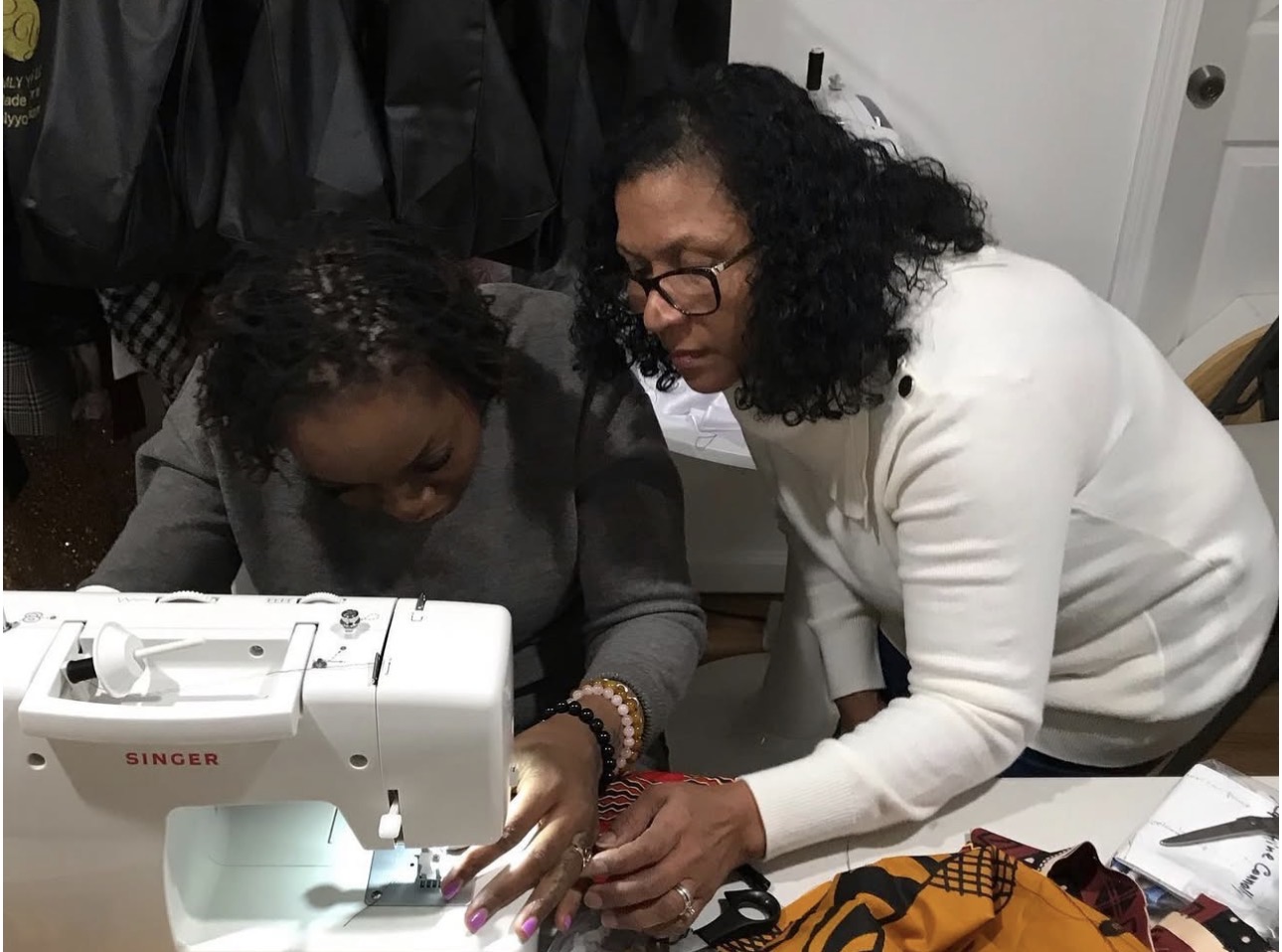 Lorraine guiding a student at a Singer sewing machine