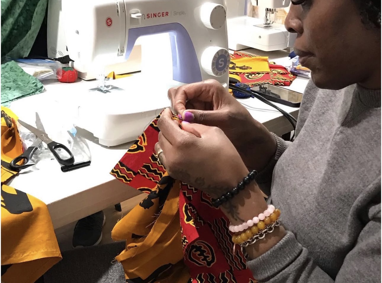 Student hand-stitching detail on African print fabric