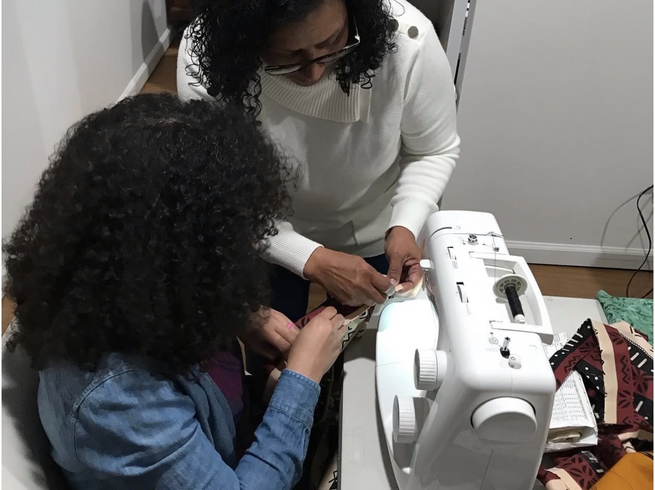 Lorraine teaching a young student to sew